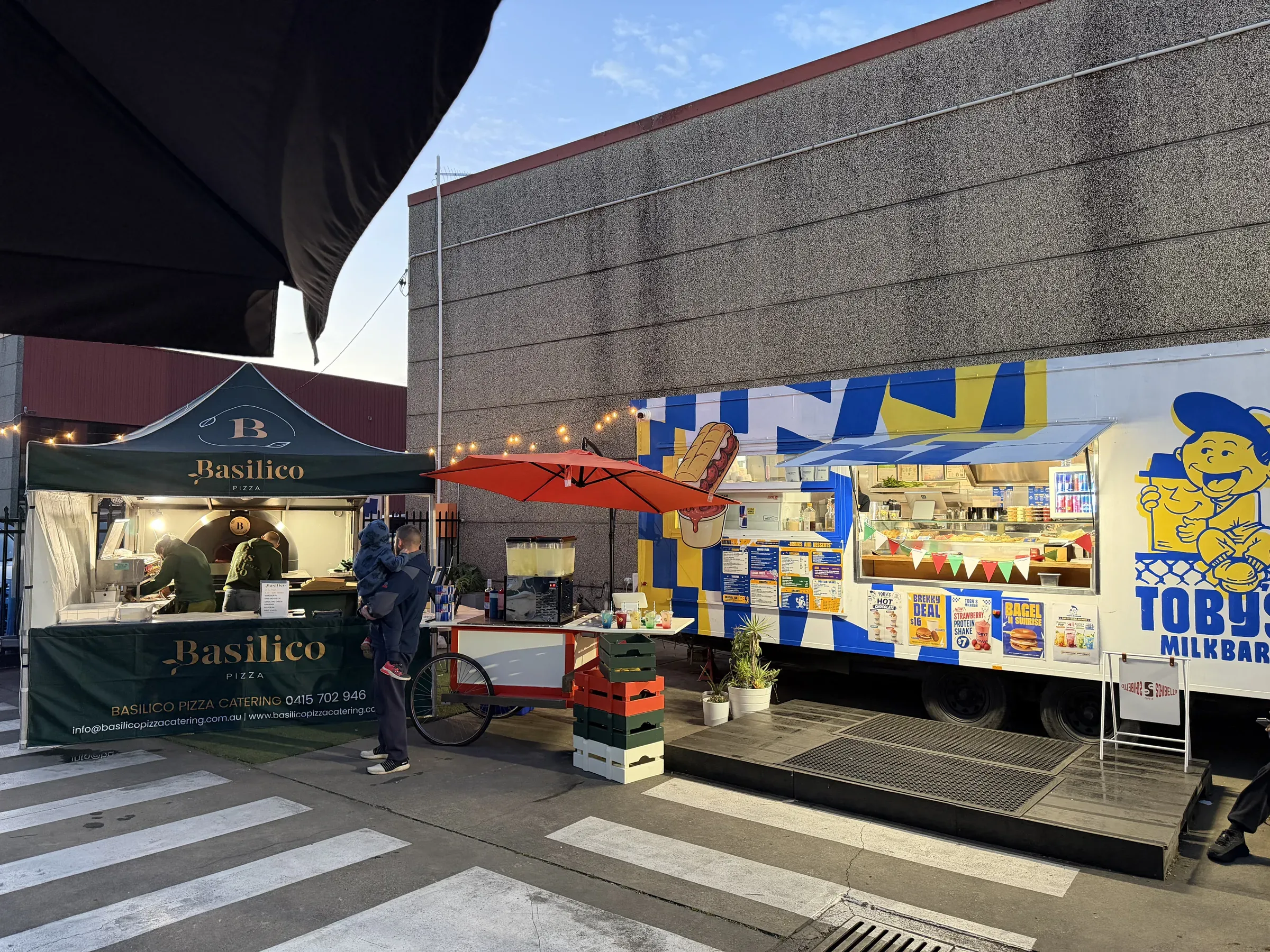 Toby's Little Italy setup at Prestons — Basilico pizza tent, drink cart, and Toby's Milkbar trailer under string lights